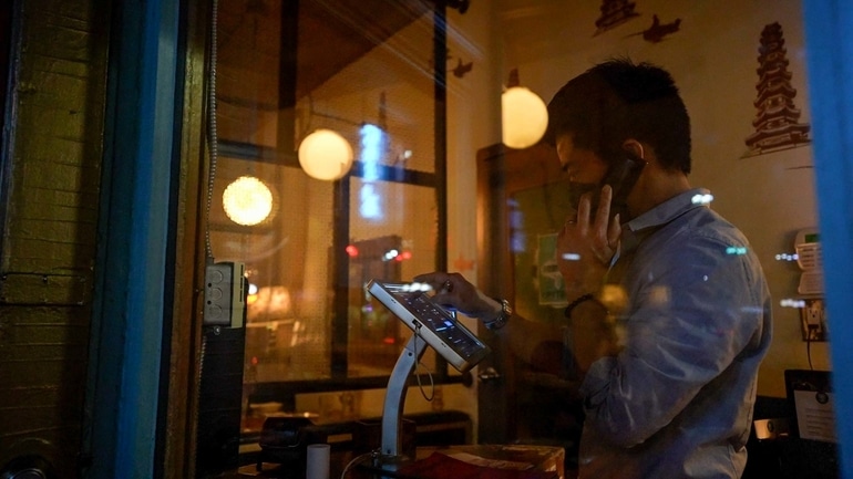 DaiLo restaurant General Manager Trevor Chen using a TouchBistro POS while talking on the phone.