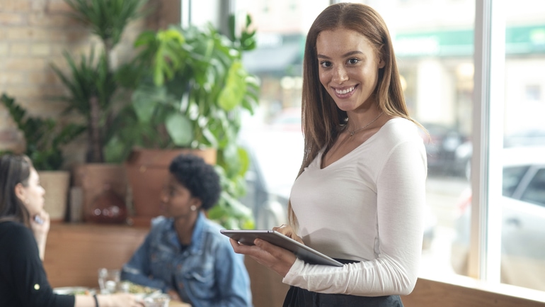 A waitress holding a POS tablet in a restaurant.